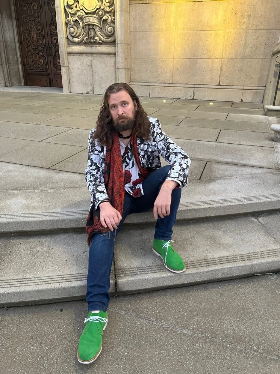 Erik Fuhrer sitting on stone steps in a floral blazer and green shoes