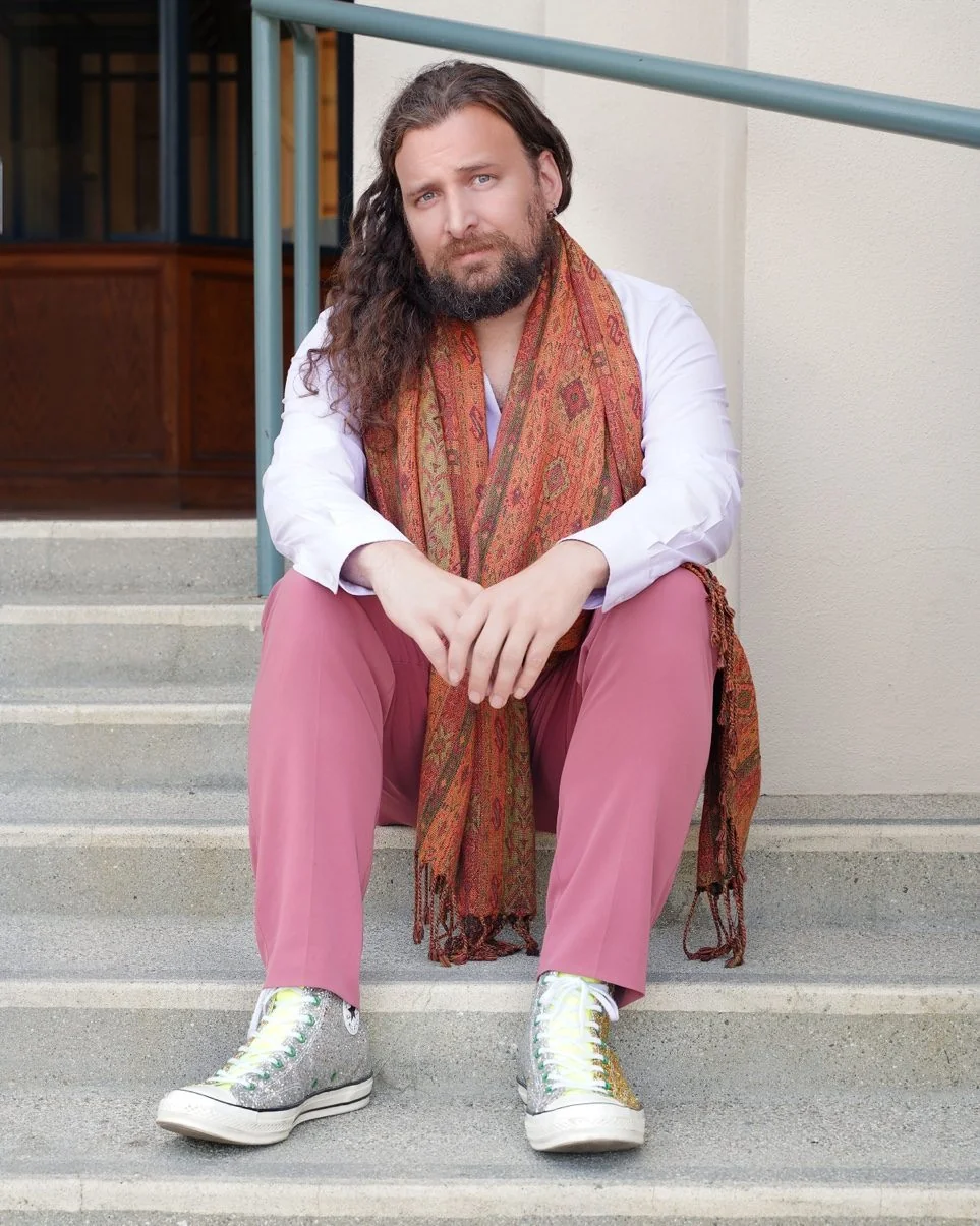 Poet Erik Fuhrer sitting on steps in pink pants and glitter Converse